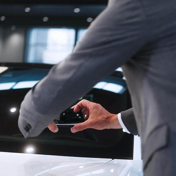 Looking from behind, a man is using PAVE on their phone to inspect a car